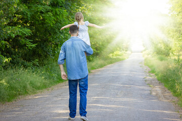 A Happy child on the shoulders of a parent in nature on the way to travel