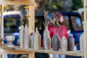Wood turned vases for sale at a public local farmers market with dried and fresh flowers in them