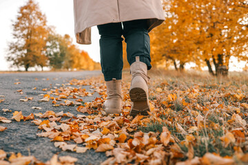 A man walks along an autumn road, boots close-up
