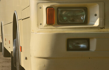 Photo of the hull of a large and long yellow bus. Close-up front view of a passenger vehicle for transportation and tourism