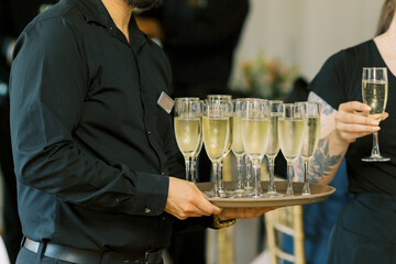 The waiter is serving champagne during wedding reception. 