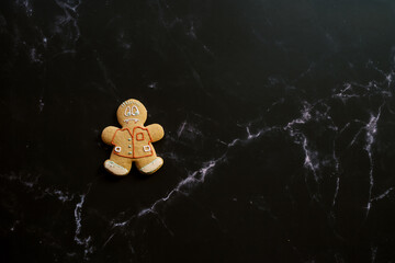 Vampire gingerbread man lies on a black veined marble background