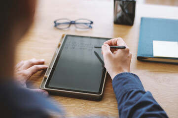 Hands of entrepreneur writing plans for the day on tablet computer
