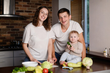 A happy family with a child prepares a healthy salad from fresh vegetables in the kitchen.Proper nutrition.Diet concept.