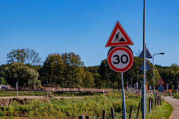 Traffic sign indicating: maximum speed 30 and men working, work zone in road construction and...
