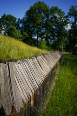 Wooden fence over meadow with trees in the background