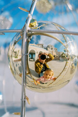 Dad and little girl are photographed in the reflection of a glass ball