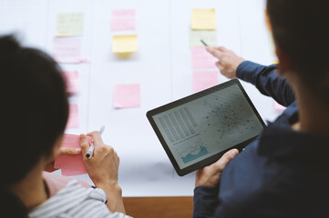 Tablet computer with scatter diagram in hands of businessman talking to colleague in meeting