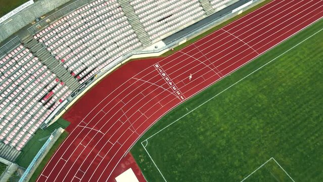 Top view of a sportswoman running on a treadmill. A runner trains in an outdoor track arena. Aerial view