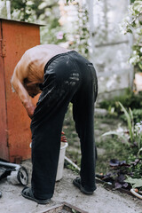 An elderly old gray-haired man, a repairman, a cleaner, works outdoors.