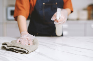 Person cleaning kitchen counter with disinfectant spray