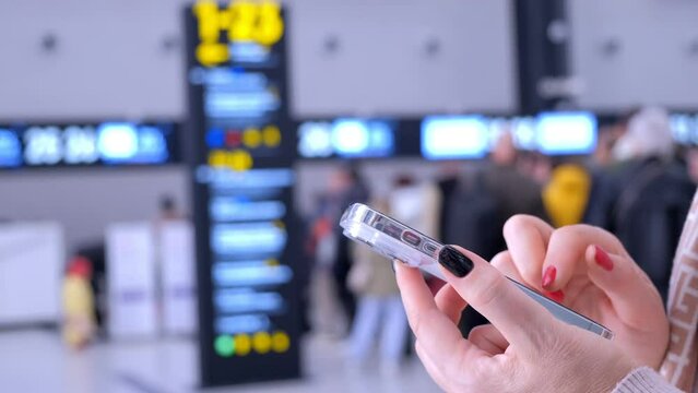 Close-up. People in international airport. Female traveler look at phone, search for boarding pass or flight cancelation information. 4K
