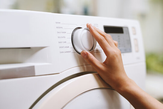 Hand of person choosing right washing cycle on machine
