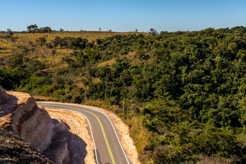 Curve of the road in Serra de Avencas, with the sandstone wall on one side and the vegetation on...
