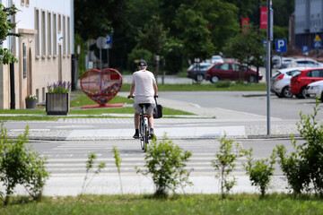 Starszy mężczyzna na rowerze jedzie  po przejściu dla pieszych.