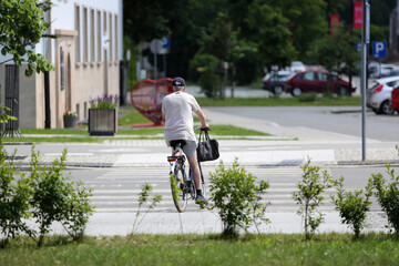 Starszy mężczyzna jedzie rowerem przez przejście dla pieszych. - obrazy, fototapety, plakaty