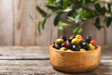 A set of green, red and black olives on  background. Various types of olives in bowls and fresh olive leaves. Vegan. Olive fruits. Place for text. Copy space.