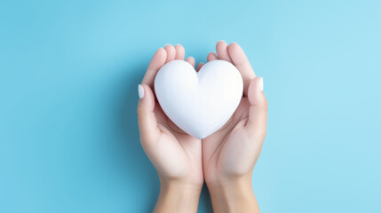 Woman holding white heart on blue background, top view.