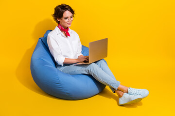 Photo of adorable cute girl sitting soft pouf using modern device wireless netbook macbook empty...