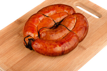 Homemade fried sausages tied with sausage string on a wooden cutting board.