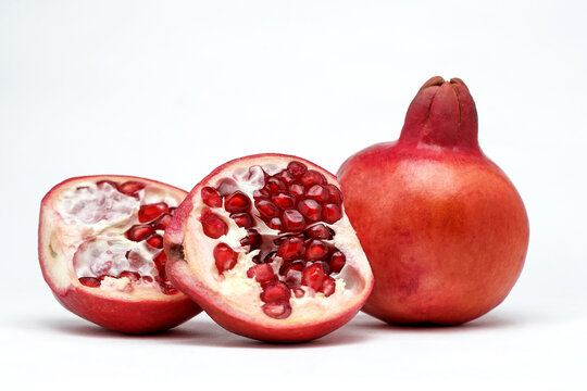 Several ripe pomegranate fruits and an open  whole pomegranate, Juicy pomegranate seeds on table, Fresh ripe Pomegranate half isolated on white background, Healthy pomegranates fruit garnet, side view