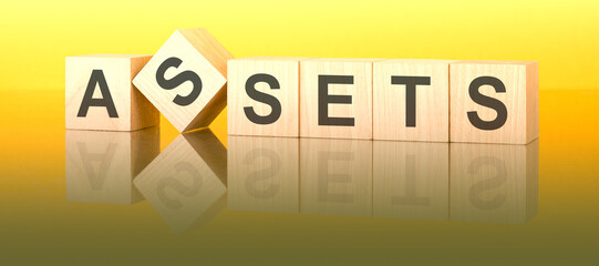 assets text on wooden blocks on a yellow table. light background