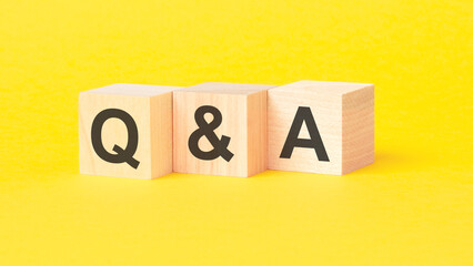 QA - Question and Answer symbol. wooden cubes with words. beautiful yellow background. business concept. copy space.