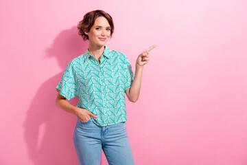Portrait of charming young lady direct finger empty space advertisement store wear casual shirt jeans isolated pink color background