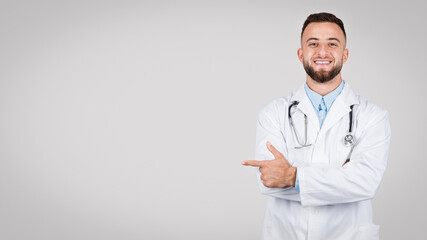 Young caucasian doc man pointing to side at free space, grey background, panorama