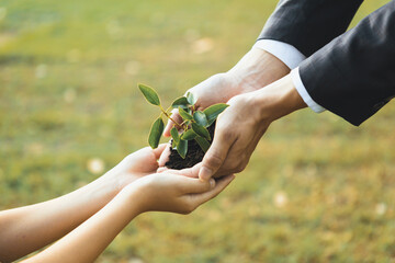 Businessman handing plant or sprout to young boy as eco company committed to corporate social...