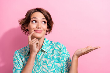 Photo of lovely creative minded girl finger touch chin look arm hold empty space isolated on pink color background
