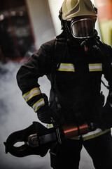 Fireman portrait wearing full equipment with oxygen mask and power hydraulic cutting tool. Smoke...