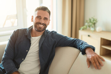 Fototapeta premium Happy middle aged guy sitting on cozy couch at home