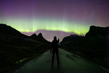 Northern lights and woman in Trollstigen road, South Norway, Europe