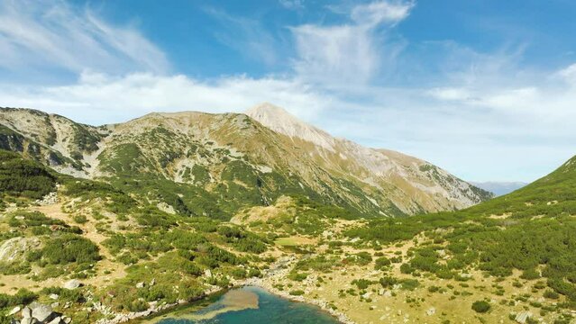 Aerial timelapse - moving towards a mountain range over a lake with elongated slim clouds floating in the opposite direction. Shot in Pirin Mountains in Bulgaria.