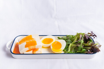 Vietnamese tofu with sunny eggs and salad leaves served in tray isolated on background side view of vietnamese food