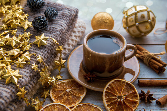 Christmas mood, holiday atmosphere. Coffee mug, Christmas decor, plaid, cones, cinnamon, star anise, walnuts against the background of a frosted window.