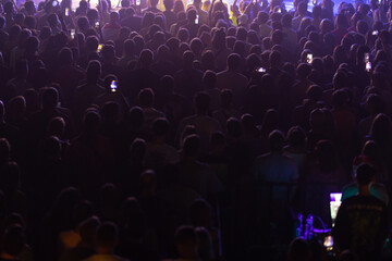 Fototapeta na wymiar A crowd of spectators watching a performance in dim light.