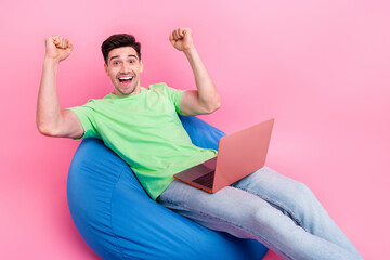 Photo of young man professional programmer raised fists up achieved final results using laptop isolated over pink color background