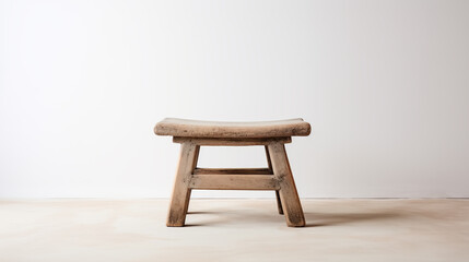 Old low Chinese wooden stool in an empty room with white wall and floor. Traditional craft, handmade furniture. Copy space.