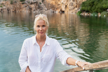 Beautiful blonde girl in a white cotton shirt on the mineral natural lake Vouliagmeni.