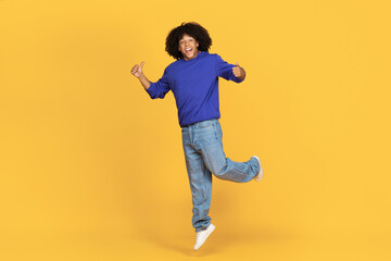 Fototapeta na wymiar Joyful Young Black Man Jumping In Air And Showing Thumbs Up