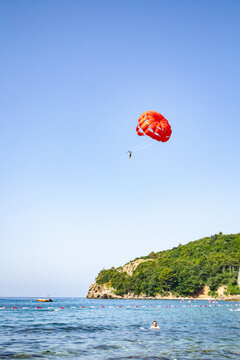 red parachute and blue sky, parasailing in Budva, Montenegro, Europe