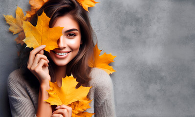 mujer sonriendo con hojas de color anaranjado en las manos, pullover de lana gris y fondo gris, concepto de otoño  - obrazy, fototapety, plakaty