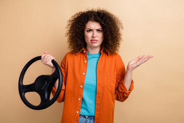 Photo of disappointed uncertain unsure girl wear trendy orange clothes hold steering wheel isolated...