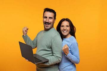 Glad senior european husband and wife with laptop, celebrate success with hand fist rise up, enjoy win