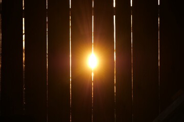 the sun shines through the fence