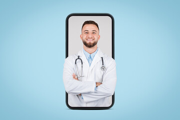 Fototapeta premium Smiling young male doc on phone screen, blue backdrop