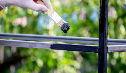 a man paints metal with black paint with a brush.