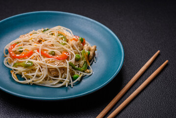 Tasty dish of Asian cuisine with rice noodles, chicken, asparagus, pepper, sesame seeds